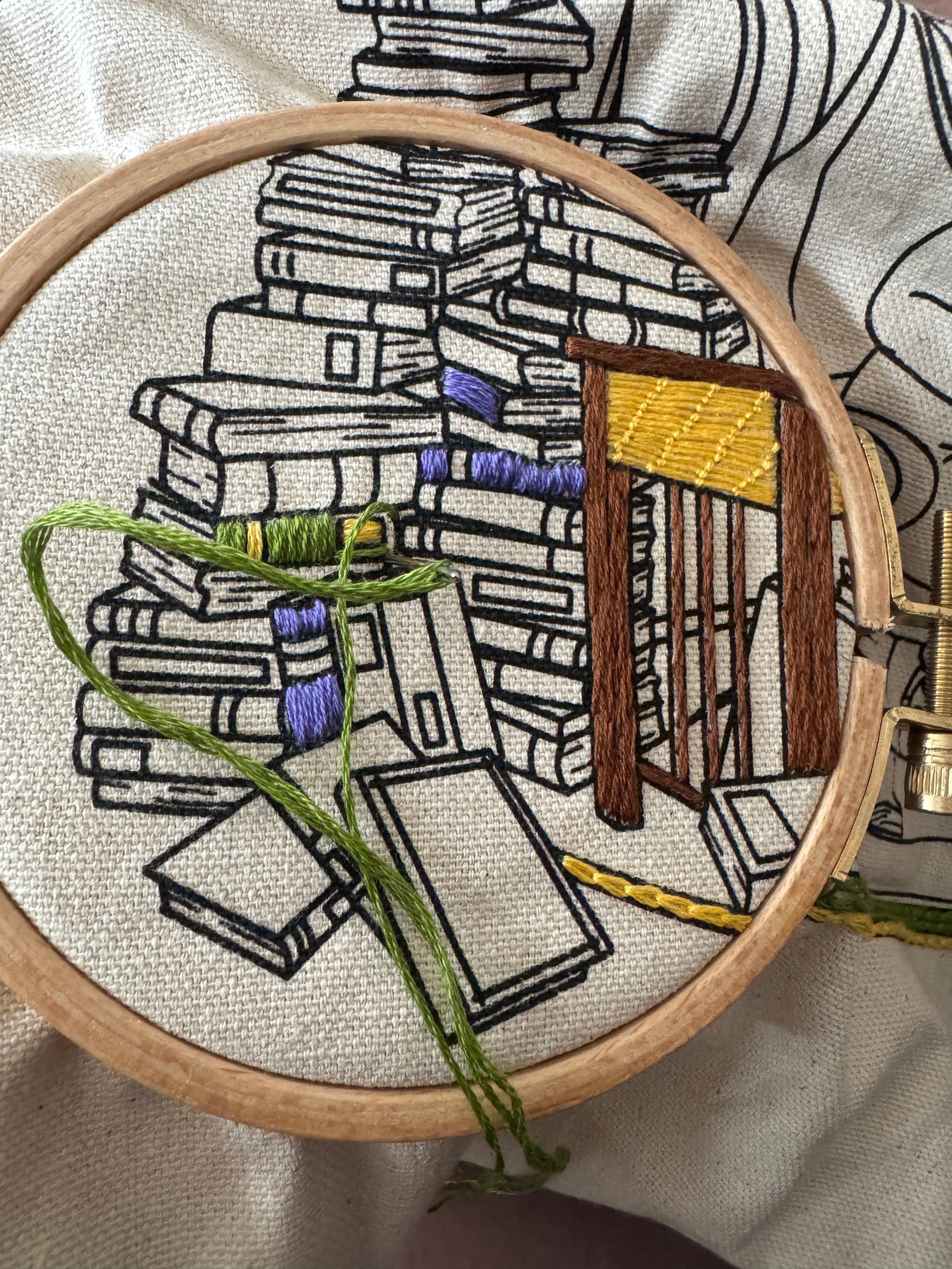 Embroidery hoop with a detailed embroidery of books and a door.