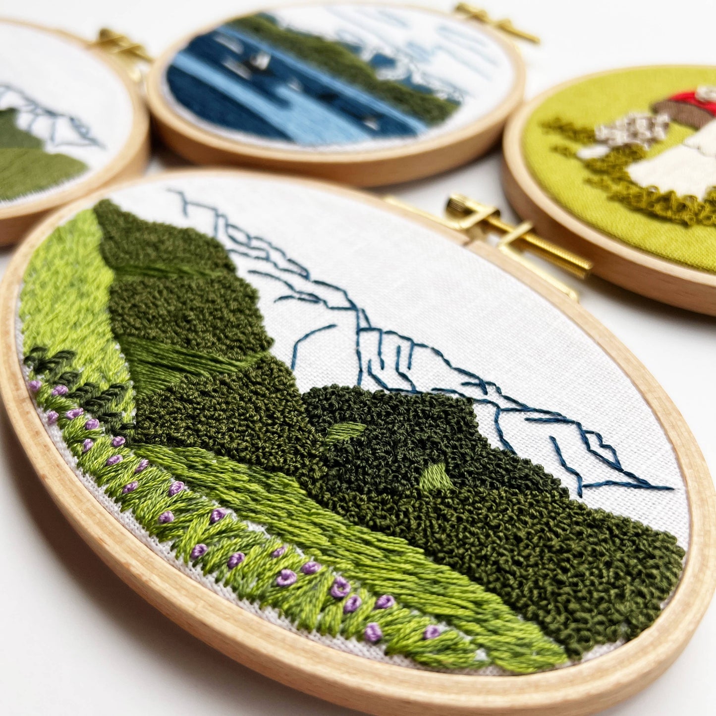 Embroidery hoops with landscape designs on a white background
