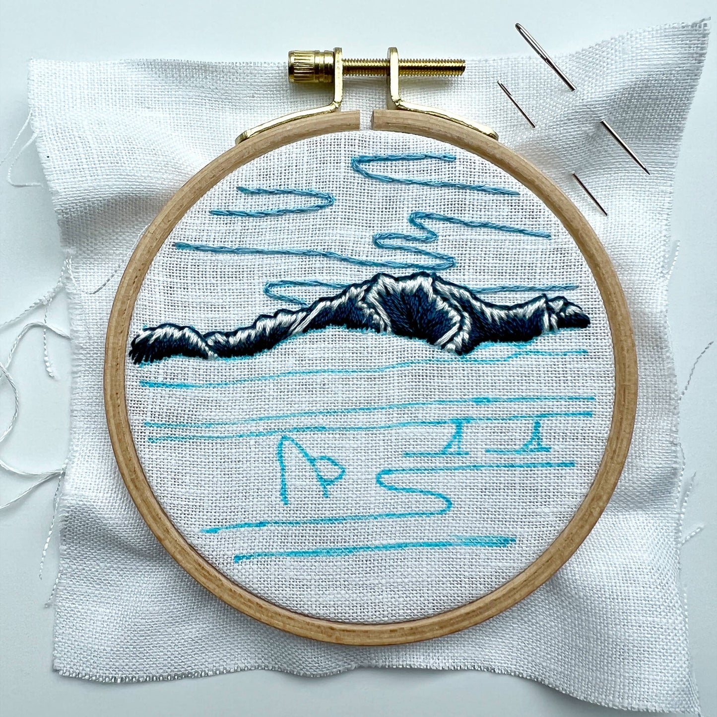 Embroidery hoop with a mountain design on white fabric