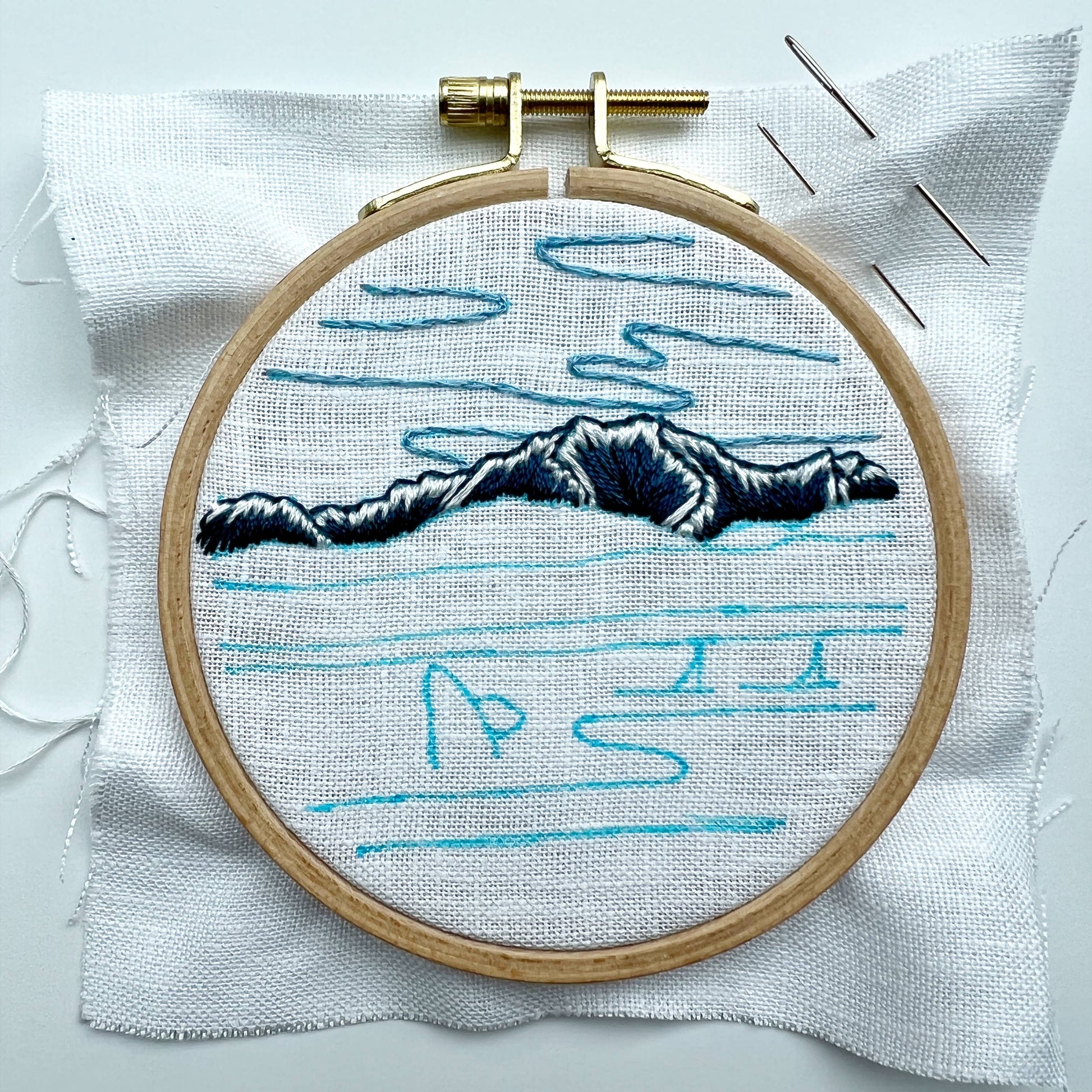 Embroidery hoop with a mountain design on white fabric