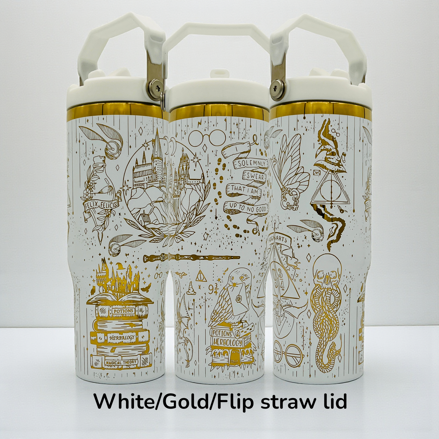 Three white bottles with gold designs featuring magical motifs and flip straw lids.