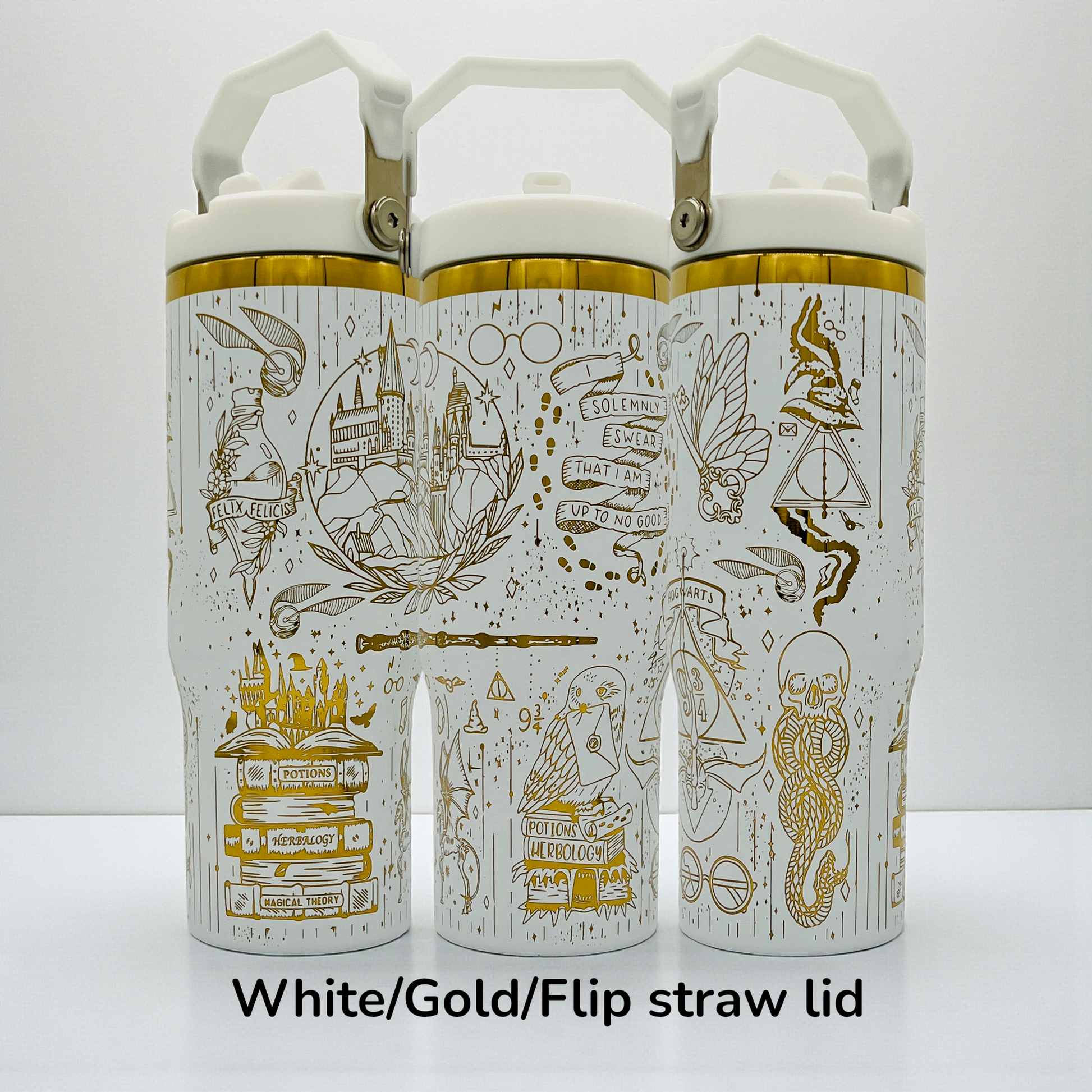 Three white bottles with gold designs featuring magical motifs and flip straw lids.