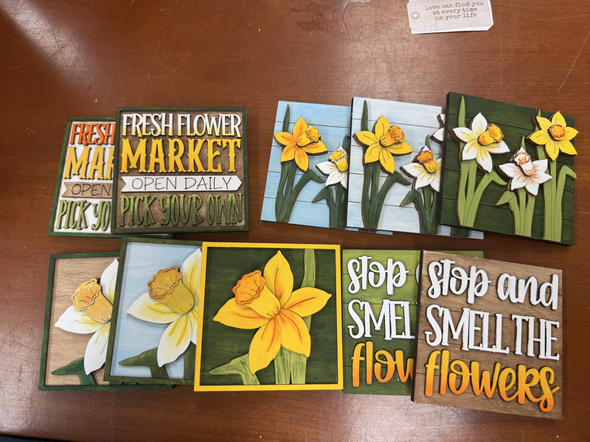 Decorative wooden signs with floral designs and text on a wooden surface