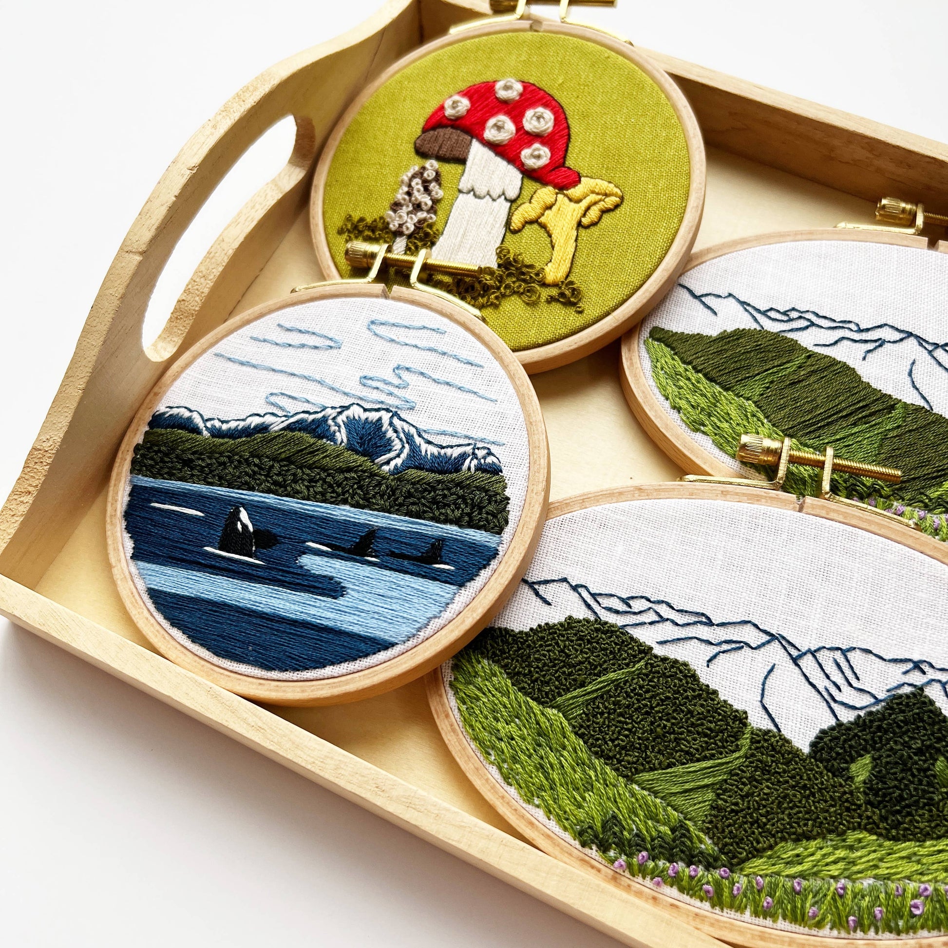 Set of embroidered scenes in wooden hoops on a white background
