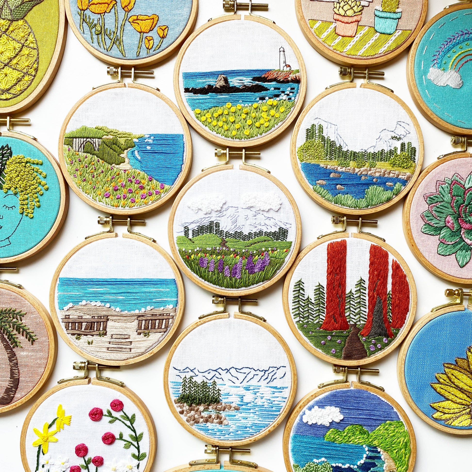 Collection of embroidered scenes in wooden hoops on a white background