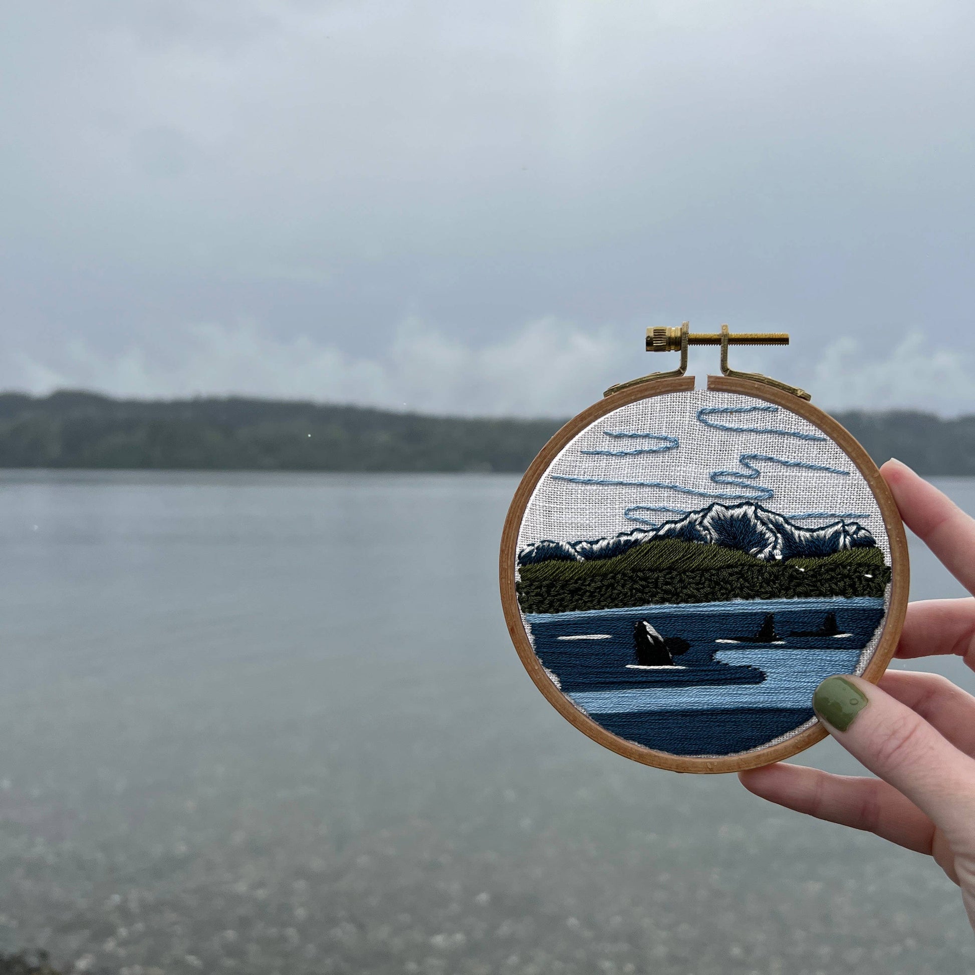 Embroidery hoop with a landscape design held over the Puget Sound