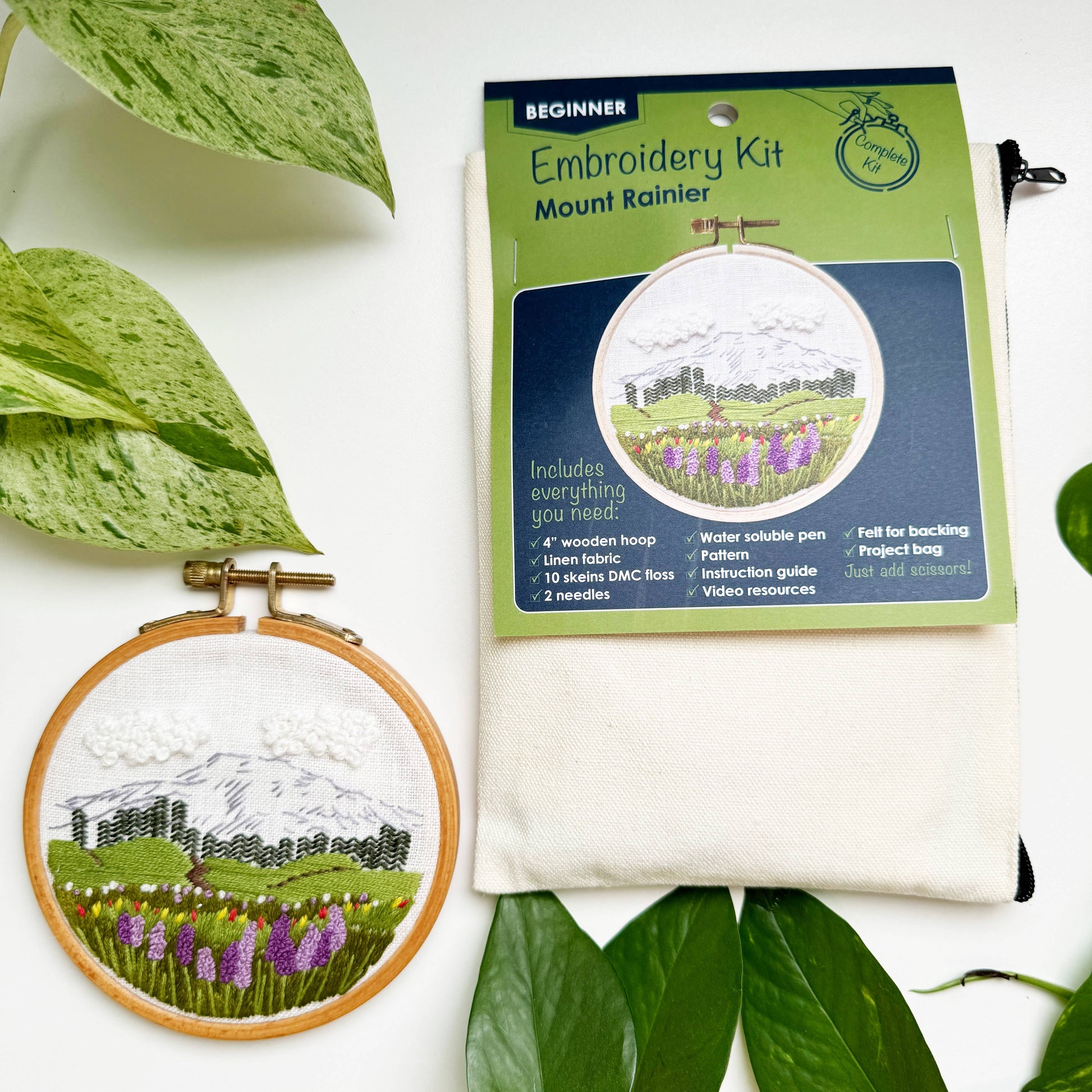 Embroidery kit with a completed embroidery of Mount Rainier surrounded by green leaves.