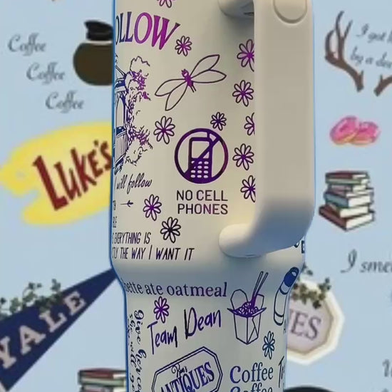 White travel mug with purple and blue graphics, featuring flowers, text, and various symbols.