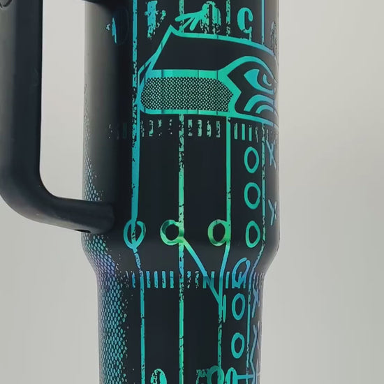 40oz Seattle Seahawks themed laser engraved tumbler. Logos with distressed field and football. Green engraving with black top color