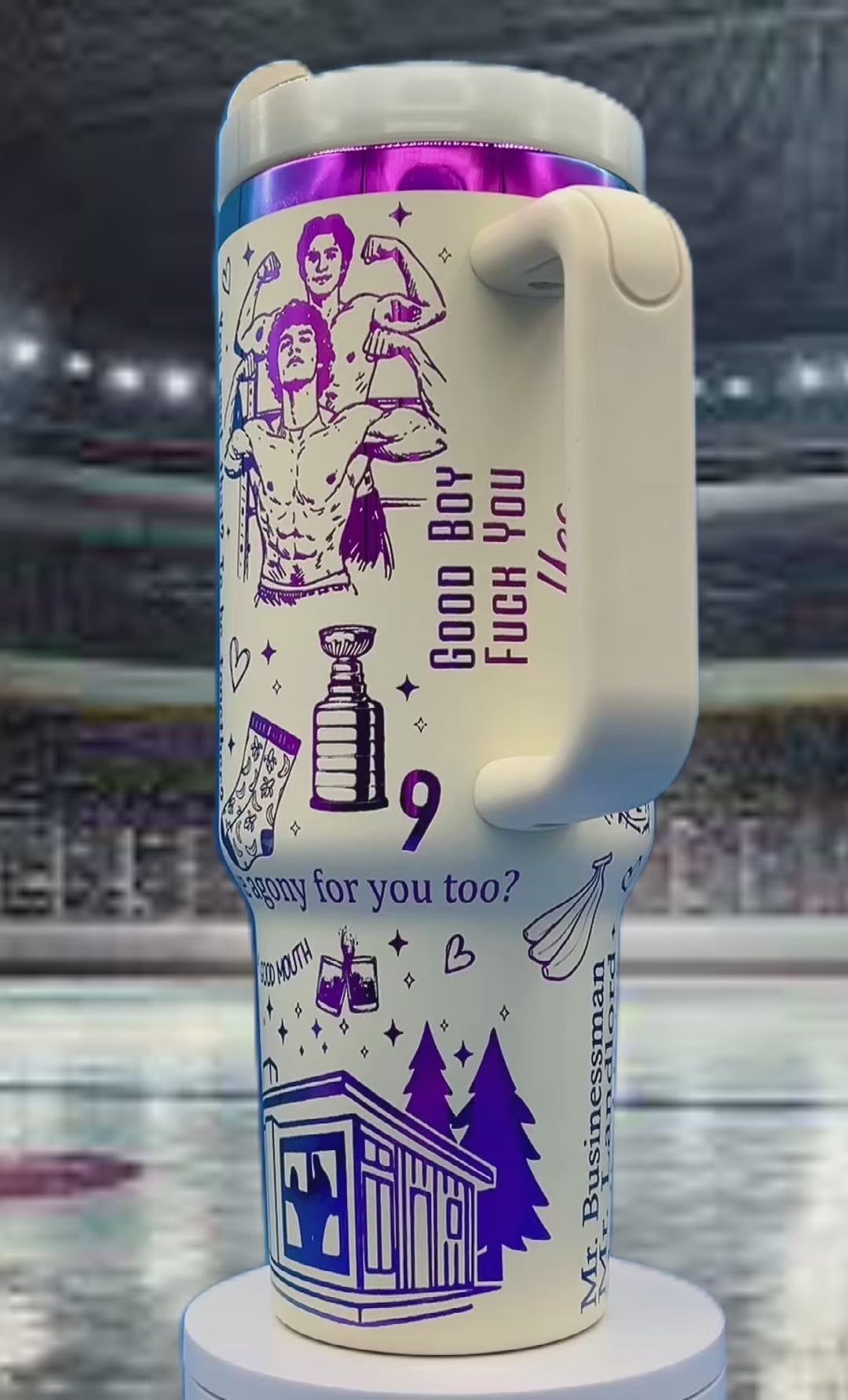 White travel mug with purple illustrations of flexing figures, trees, and a trophy, on ice rink.