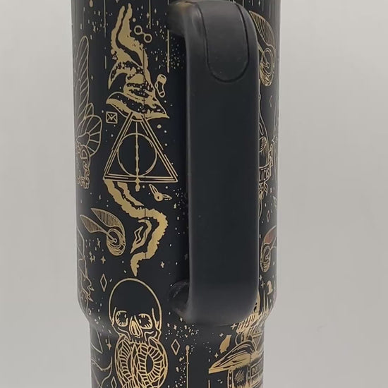 Black travel mug with gold mystical designs, featuring symbols, a snake, and geometric shapes.