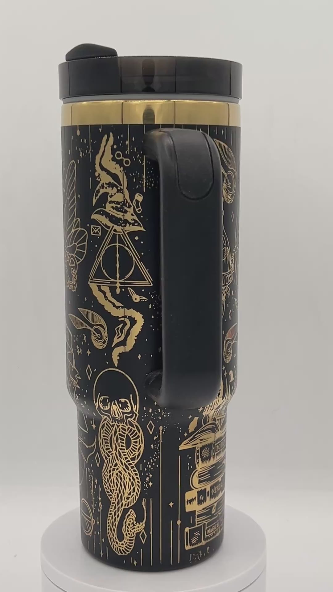 Black travel mug with gold mystical designs, featuring symbols, a snake, and geometric shapes.