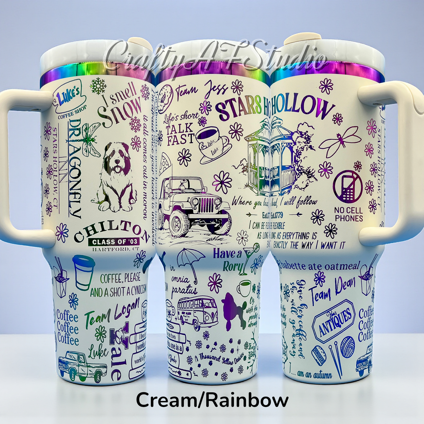 Three cream mugs with rainbow lids, featuring purple sketches and text of various icons and phrases.